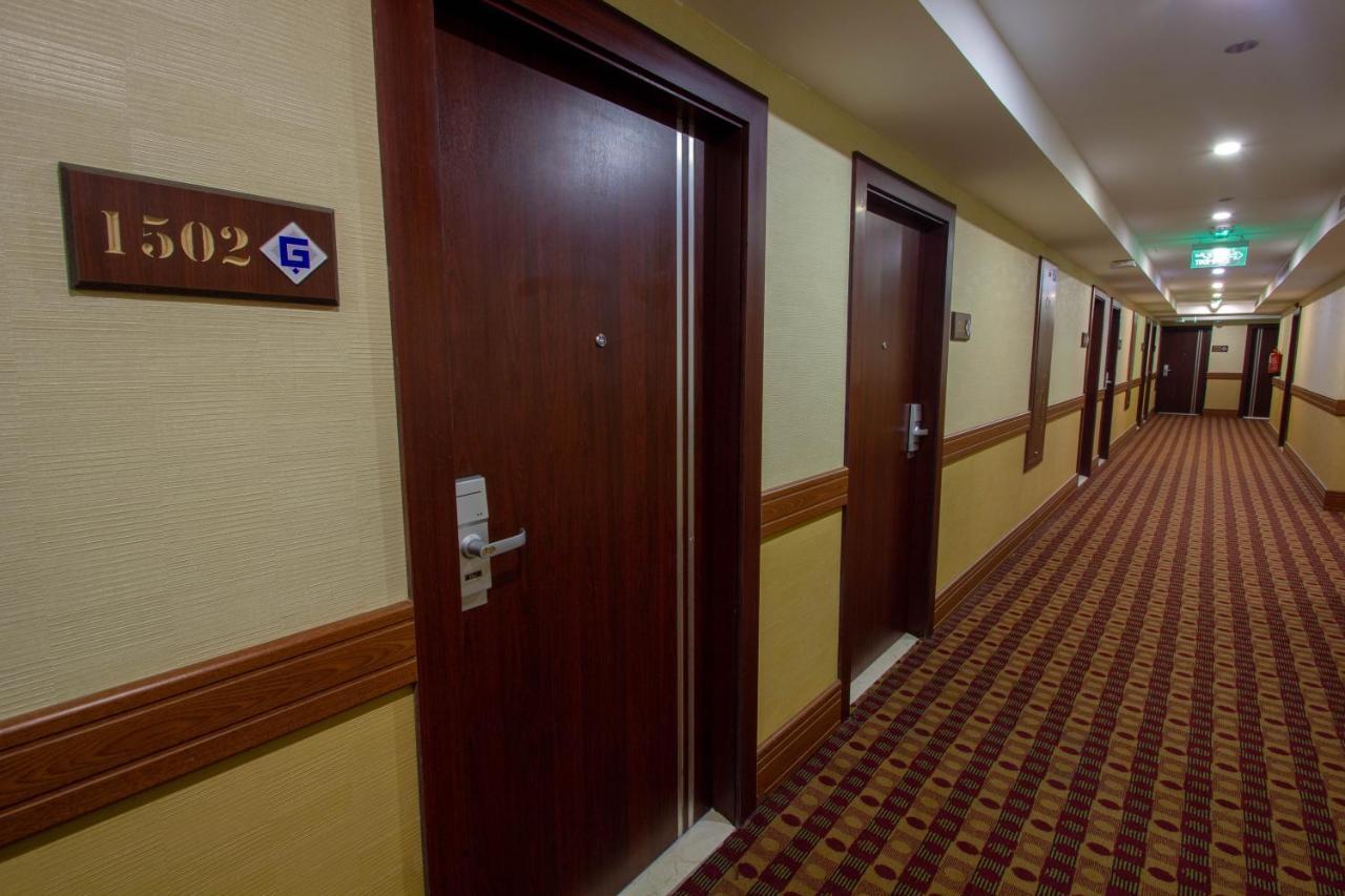 Grand Makkah Hotel La Mecque Extérieur photo The photo shows a hotel hallway with several doors. The door on the left has the number "1502" displayed on a sign above it. The walls are decorated with a light-colored wallpaper, and there is a brown carpet with a patterned design on the floor. The